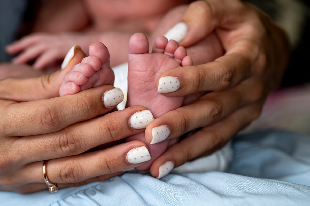 A baby's feet being held by an adult's hands.