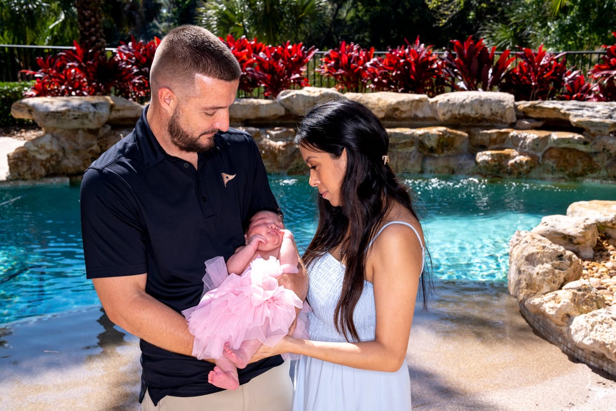 A man and woman holding a baby girl by a pool.