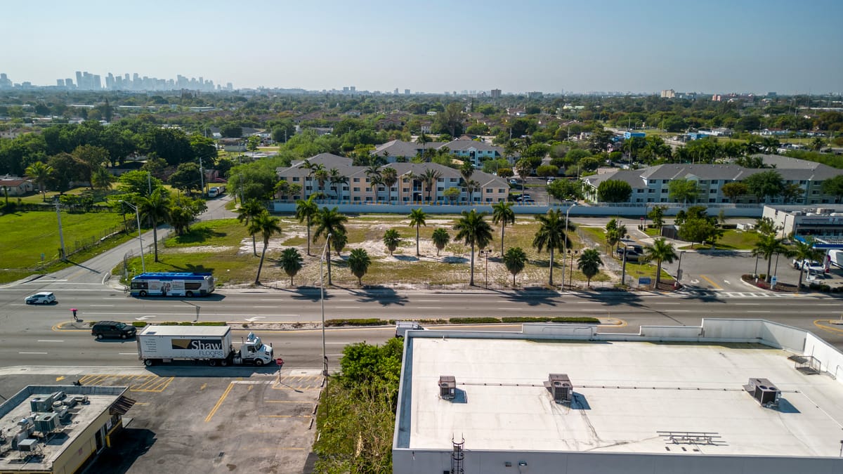 Aerial view of a suburban neighborhood with palm trees and a mix of residential and commercial buildings.