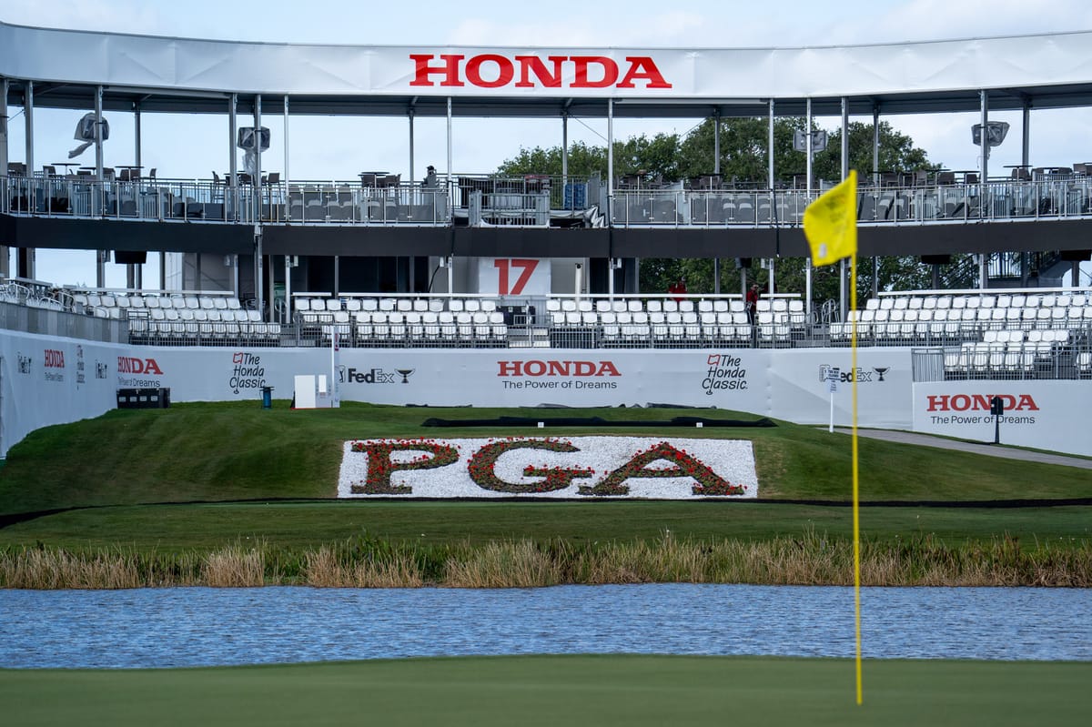 PGA National Golf course Hole 17 at the Honda Classic. a pond and a yellow flag in the foreground, and a grandstand with white seats and a Honda logo in the background.