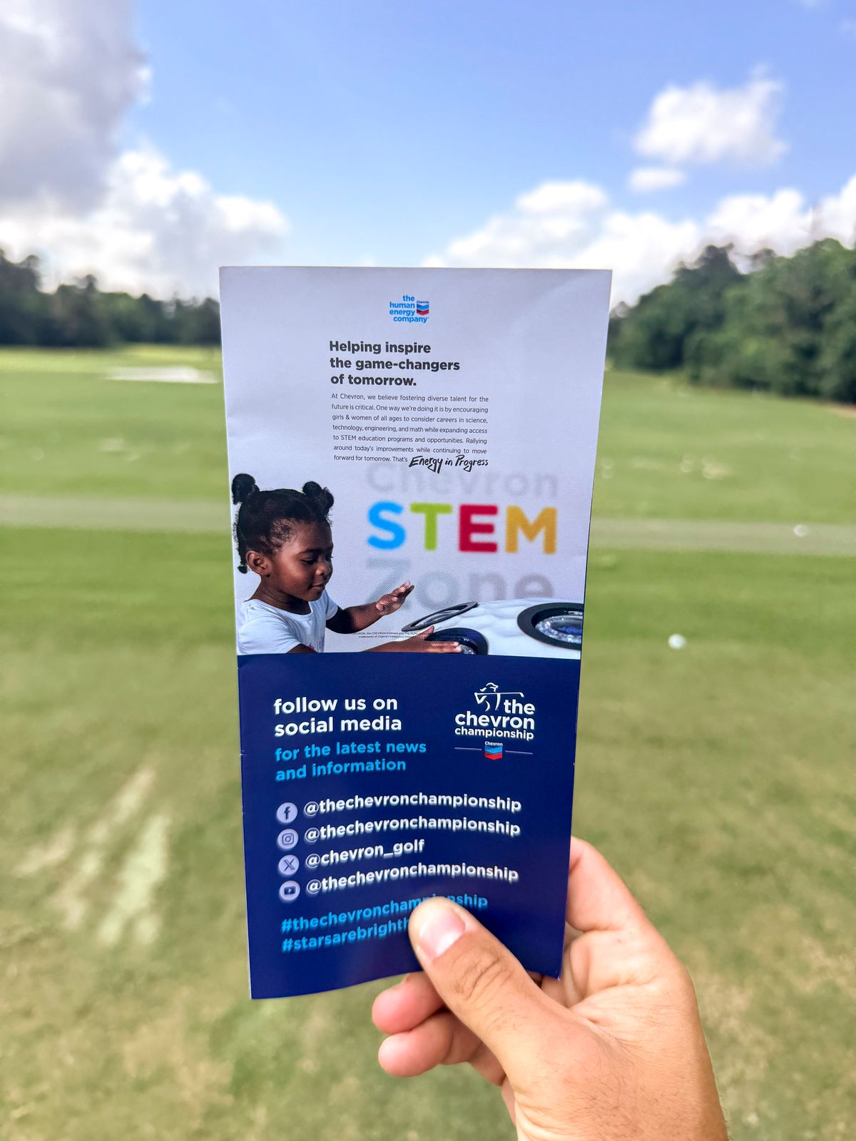 A flyer for the Chevron STEM Zone, featuring a young girl in a white t-shirt, gesturing with her hands as she sits in a white car.