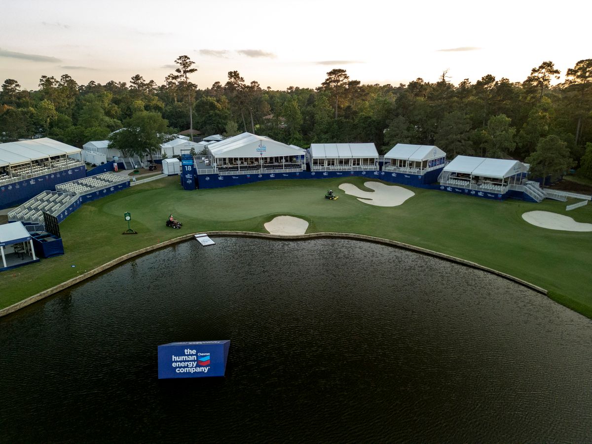 Aerial view of a golf course with a pond and trees in the background.