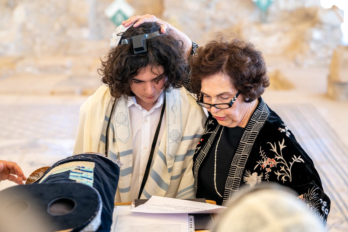 A man and woman standing in a synagogue, surrounded by stone walls and a wooden floor.